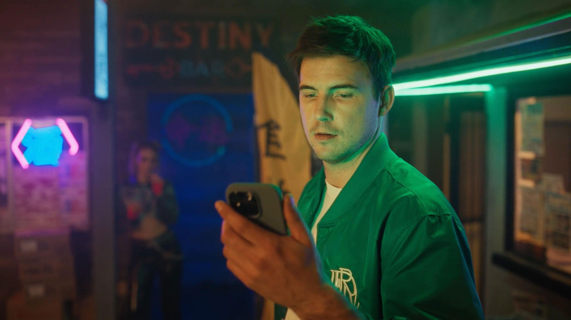 Man looking at phone in neon-lit room