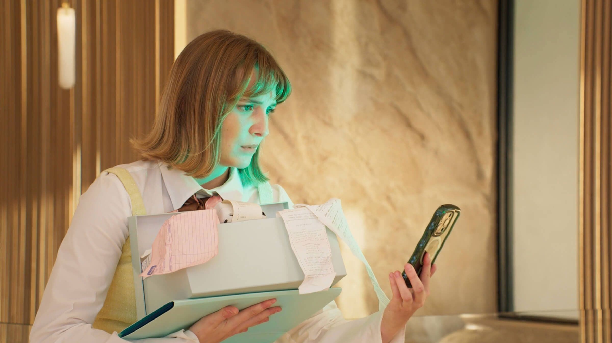 Woman holding papers and checking phone